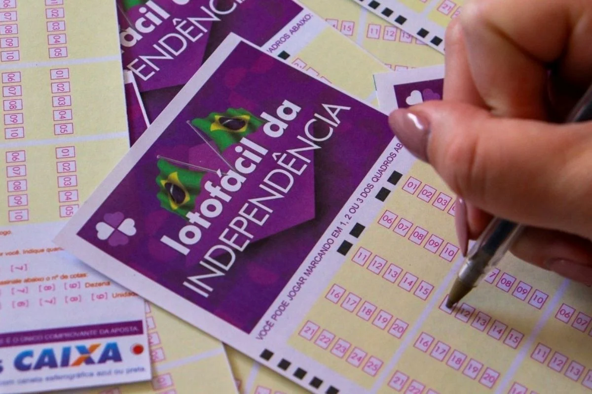 Foto colorida de mulher branca preenchendo cartela da Lotofácil da Independência - Metrópoles
