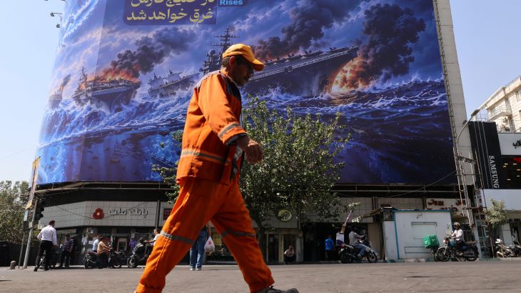 Iranian commuters pass a huge anti-US billboard reading in Persian, The devil army will be drowned in the Persian Gulf, erected on Enghelab Square in Tehran, on September 14, 2026. Iran's nuclear chief was blocked from attending an annual conference on September 14, at the headquarters of the UN's nuclear agency in Vienna due to opposition from the United States, Iranian state television said. He was due to attend the annual general conference of the International Atomic Energy Agenc